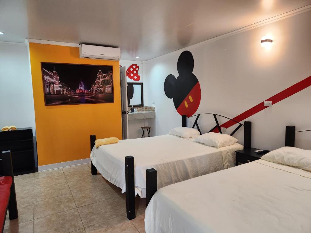 Habitación con 2 camas y una pintura en la pared. en Wally World Inn, en Comayagua