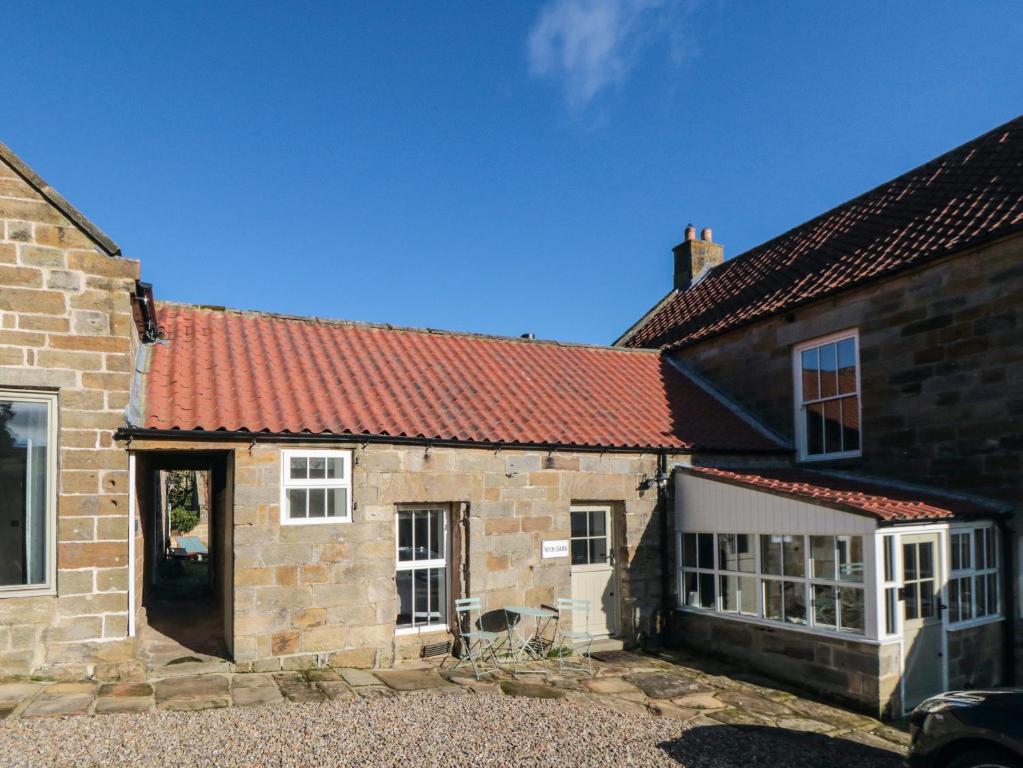 una antigua casa de piedra con techo rojo en The Nook, en Whitby