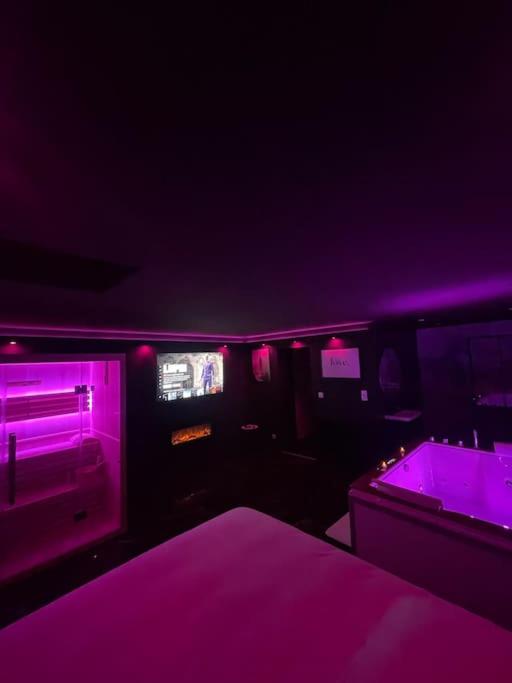 Cette chambre sombre dispose de lumières violettes et d'un lit. dans l'établissement La Suite Prestige Jacuzzi,Sauna,Netflix,Disney, à Amiens