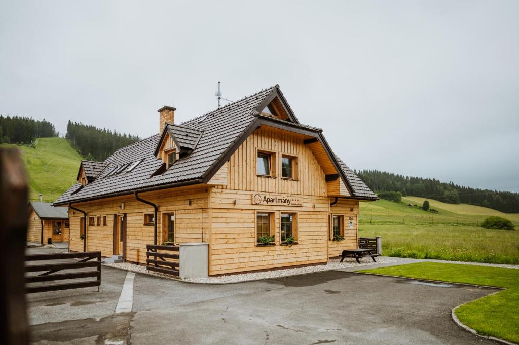 a wooden cabin with a black roof at Apartmány Velké Karlovice in Velké Karlovice