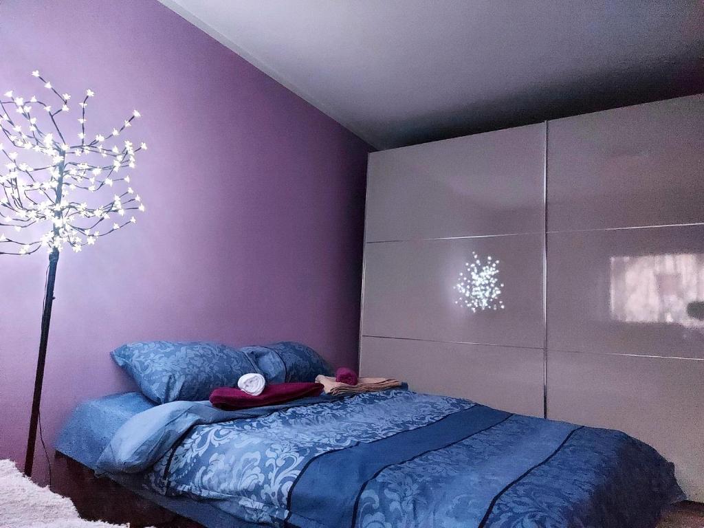 una camera con letto blu e parete viola di Quattro apartment a Zaječar