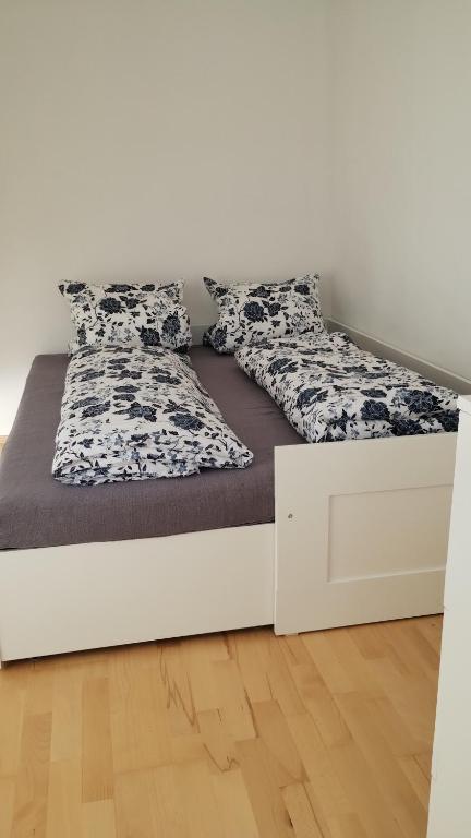 a bed in a room with a white wall at City Leaves Apartments in Sankt Aegyd am Neuwalde