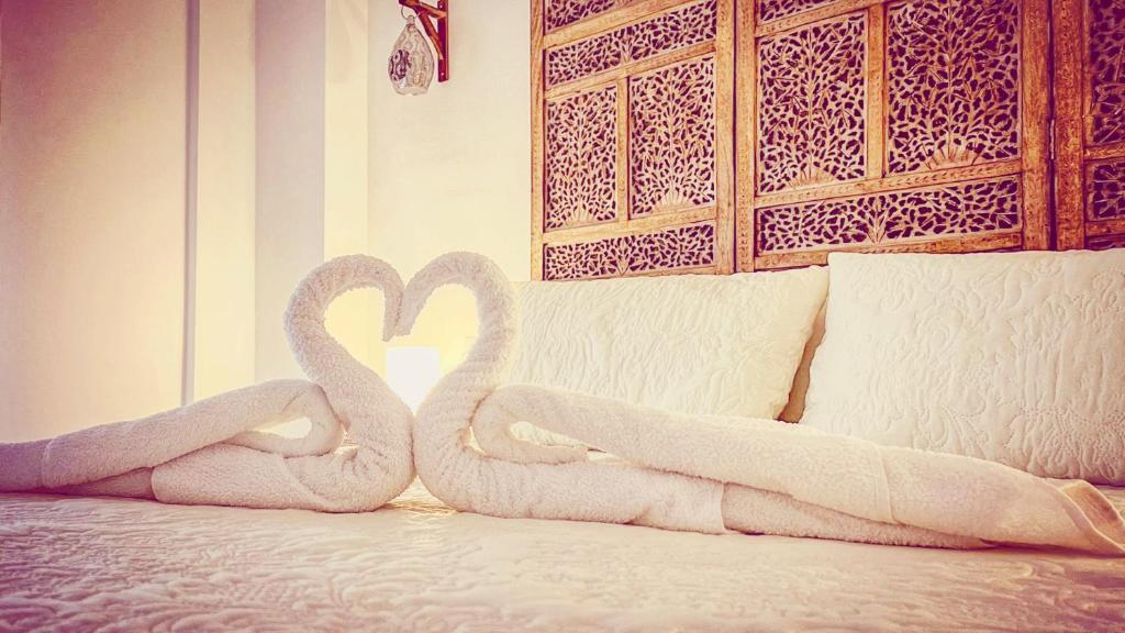 two swans are sitting on a bed with towels at Al-Ladito in Córdoba
