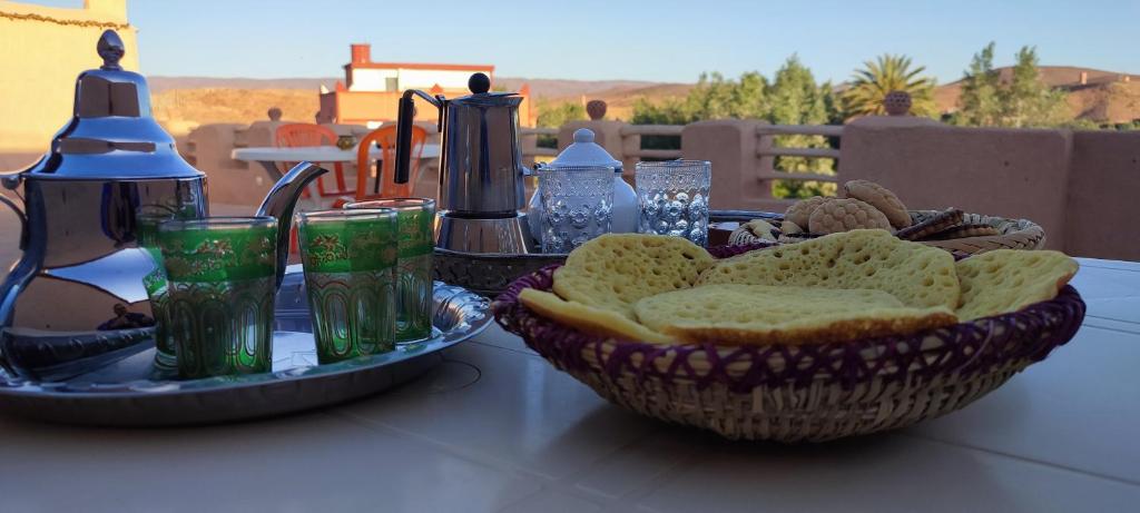 uma mesa coberta com uma cesta de pão e bebidas em Maroc des Merveilles - Chez L'habitant em El Kelaa des Mgouna