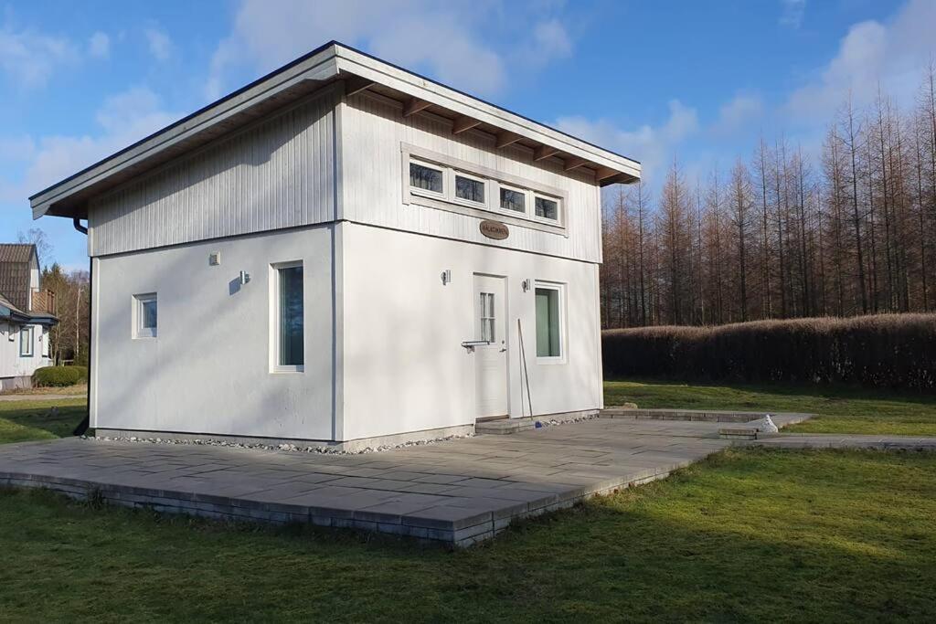 un petit bâtiment blanc dans un champ d'herbe dans l'établissement Nyhem stugan, à Våxtorp