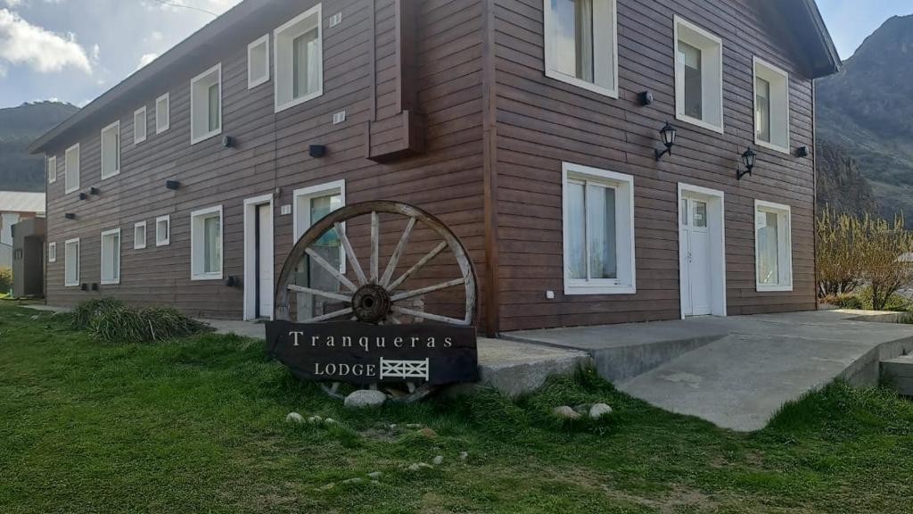 un edificio de madera con una rueda de madera delante de él en Tranqueras Lodge en El Chalten