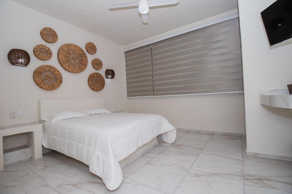 a white bedroom with a bed and a window at Paulas Suites in Ixtapa