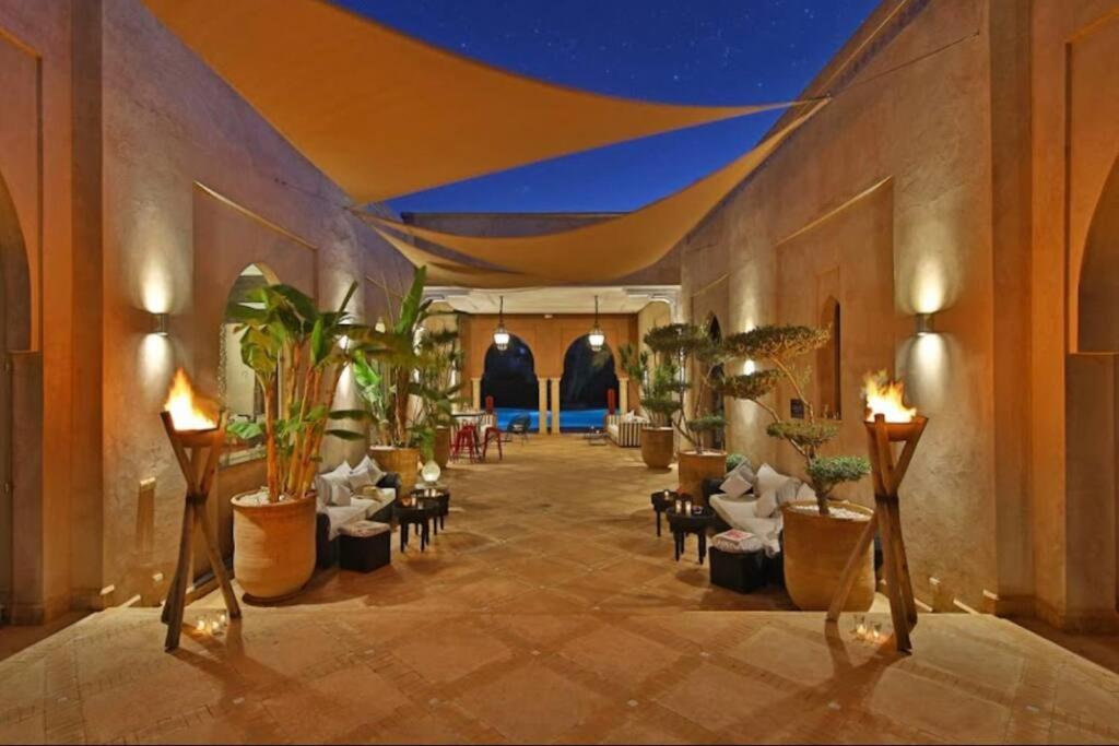 um átrio com cadeiras e vasos de plantas num edifício em Riad dar lamia em Marrakech