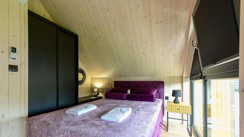 een slaapkamer met een groot bed met paarse lakens bij Lawendowe Domki Latoszyn-Zdrój Domek Bergen in Latoszyn