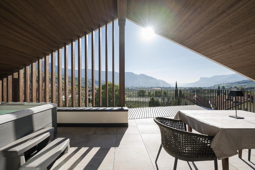 um quarto com uma mesa e cadeiras e uma grande janela em Apartsuites Rosengarten - New em Lagundo