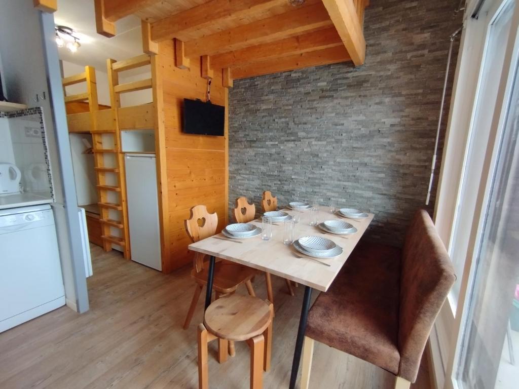 een eetkamer met een tafel en stoelen en een bakstenen muur bij Cocon Alpin - Praz de Lys Sommand in Mieussy