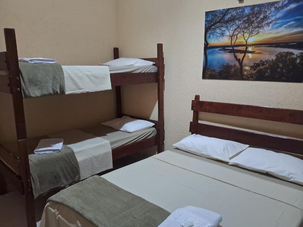 a room with three bunk beds and a picture of a tree at Pousada Sol e Lua in Caraguatatuba