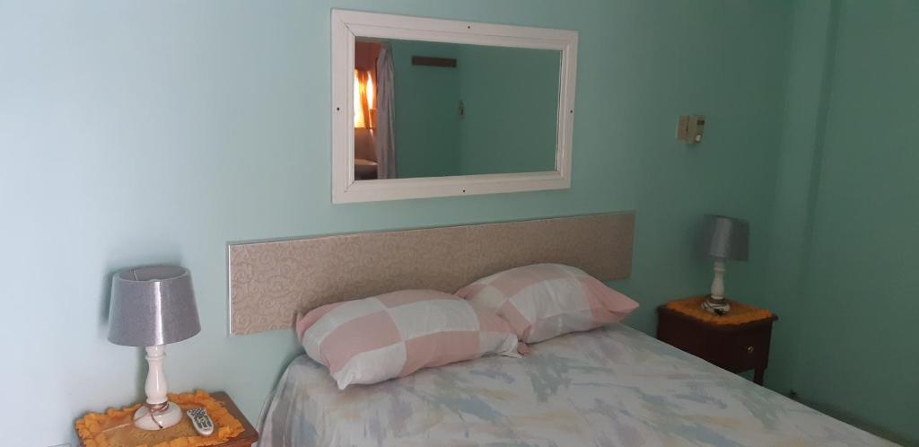 a bedroom with a bed with two pillows and a mirror at Cliff Apartment in Kingston