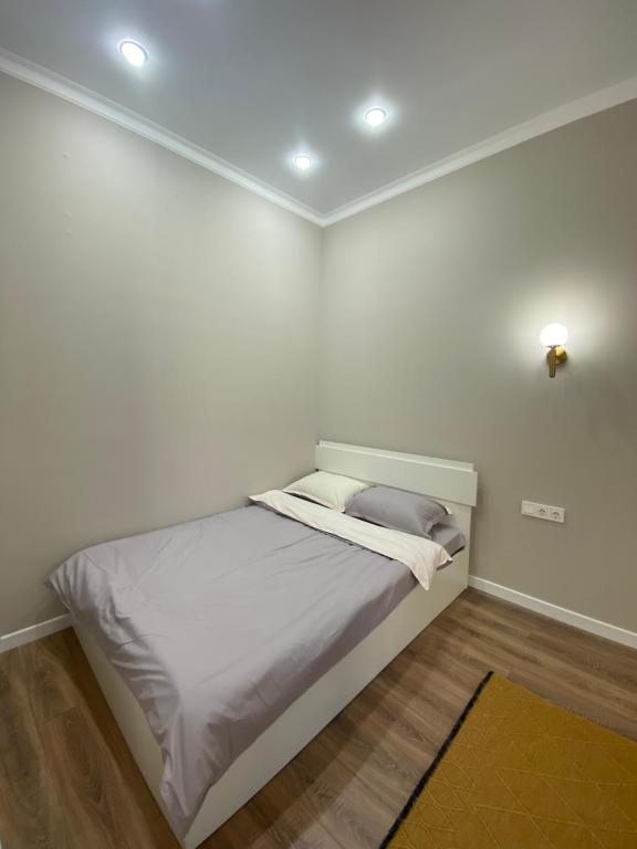 Bett in einem Zimmer mit weißen Wänden in der Unterkunft ЖК Homeland EXPO 1 комн in Taldykolʼ