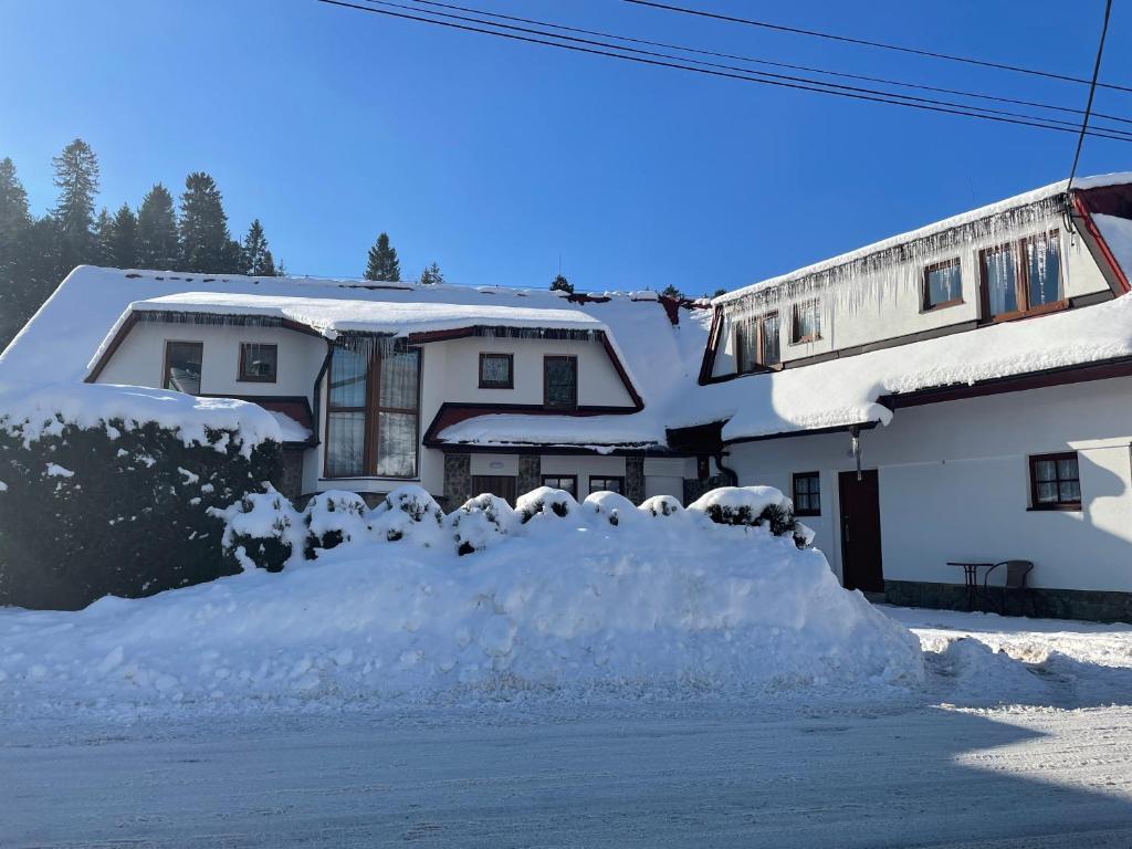 un cumulo di neve davanti a una casa di Penzión Hruboš a Habovka