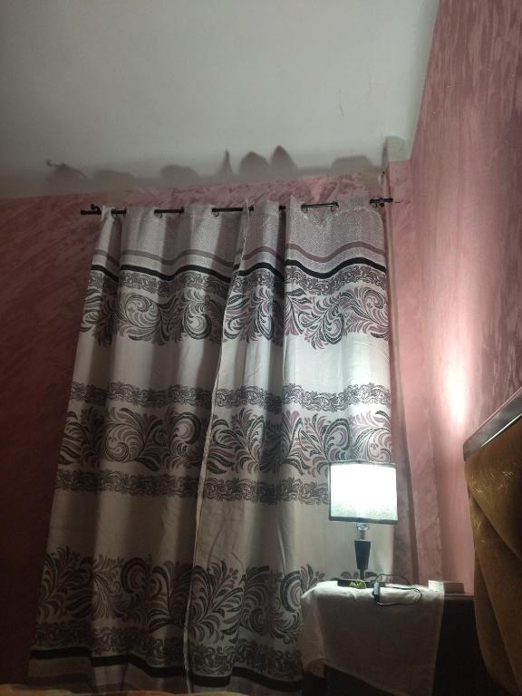 einen Vorhang in einem Zimmer mit einem Tisch und einer Lampe in der Unterkunft Cité 1 novembre in Khemis Miliana
