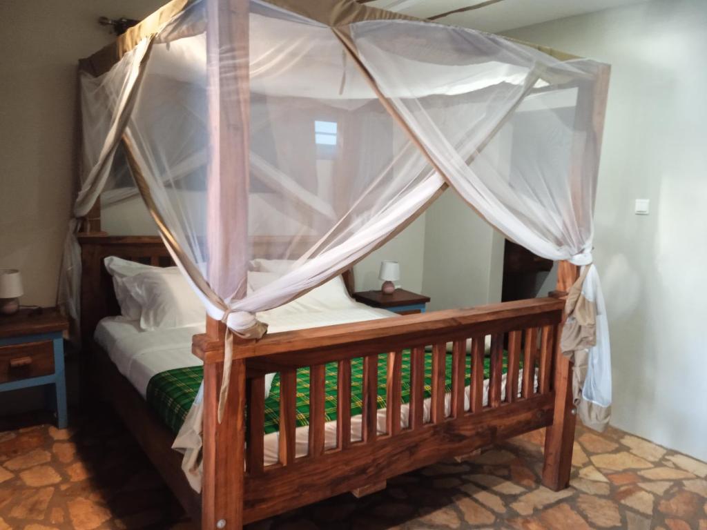 een slaapkamer met een hemelbed en een wieg bij wild-west guest house in Bunono