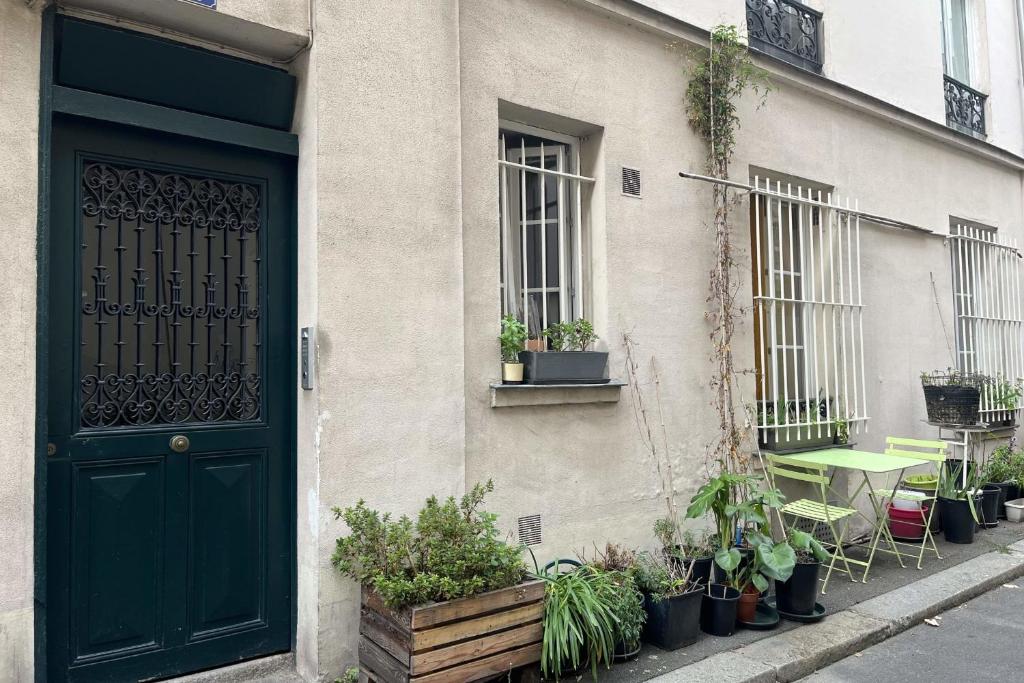 un bâtiment avec une porte verte et une table avec des plantes dans l'établissement Charming apartment in the heart of Paris, à Paris