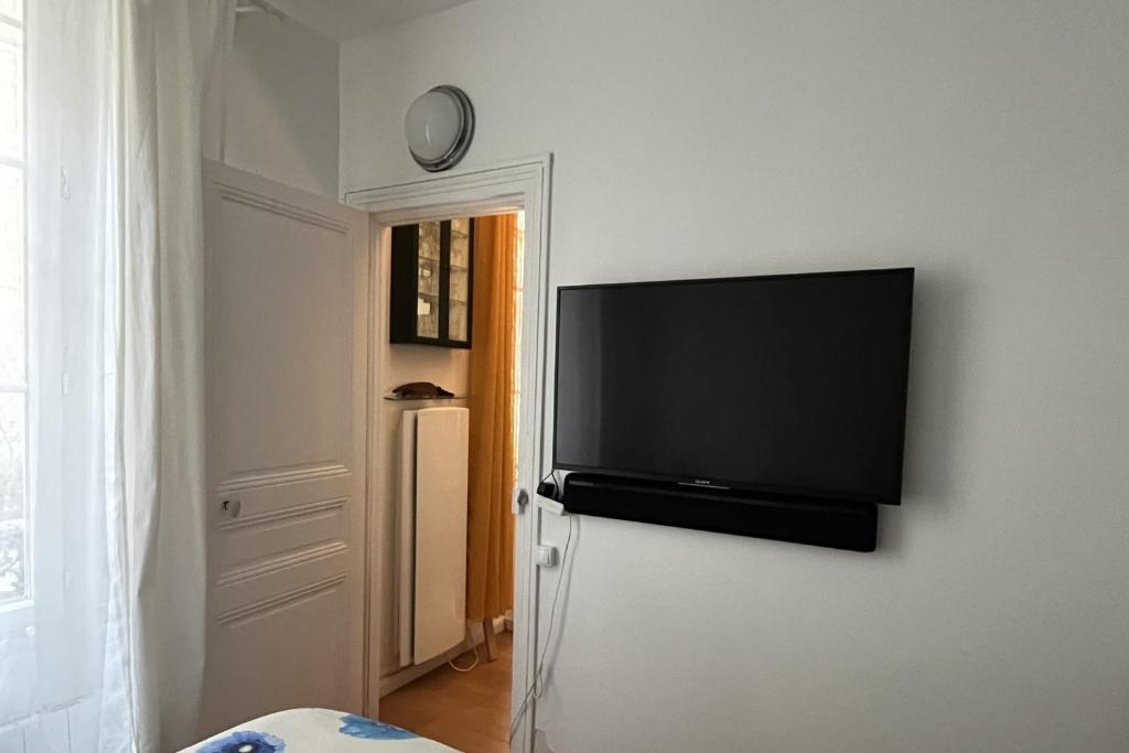 a flat screen tv hanging on a wall next to a refrigerator at Charming apartment in the heart of Paris in Paris