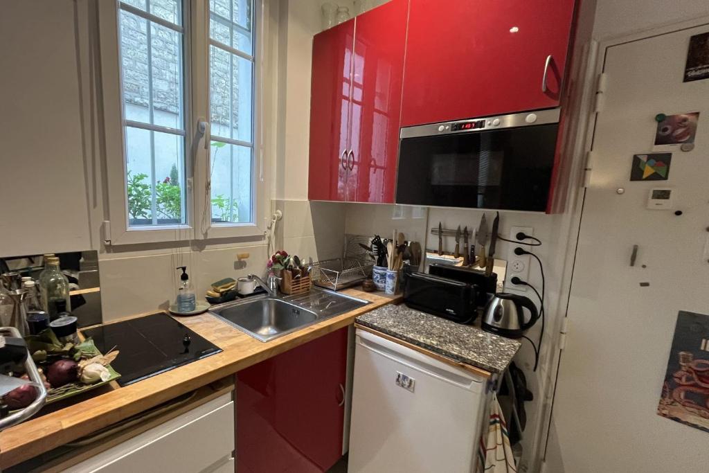 a kitchen with red cabinets and a sink at Charming apartment in the heart of Paris in Paris