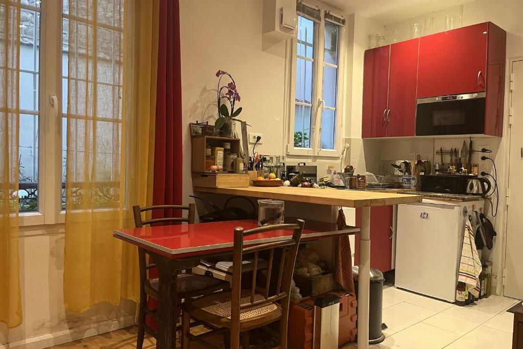 a kitchen with red cabinets and a table with chairs at Charming apartment in the heart of Paris in Paris
