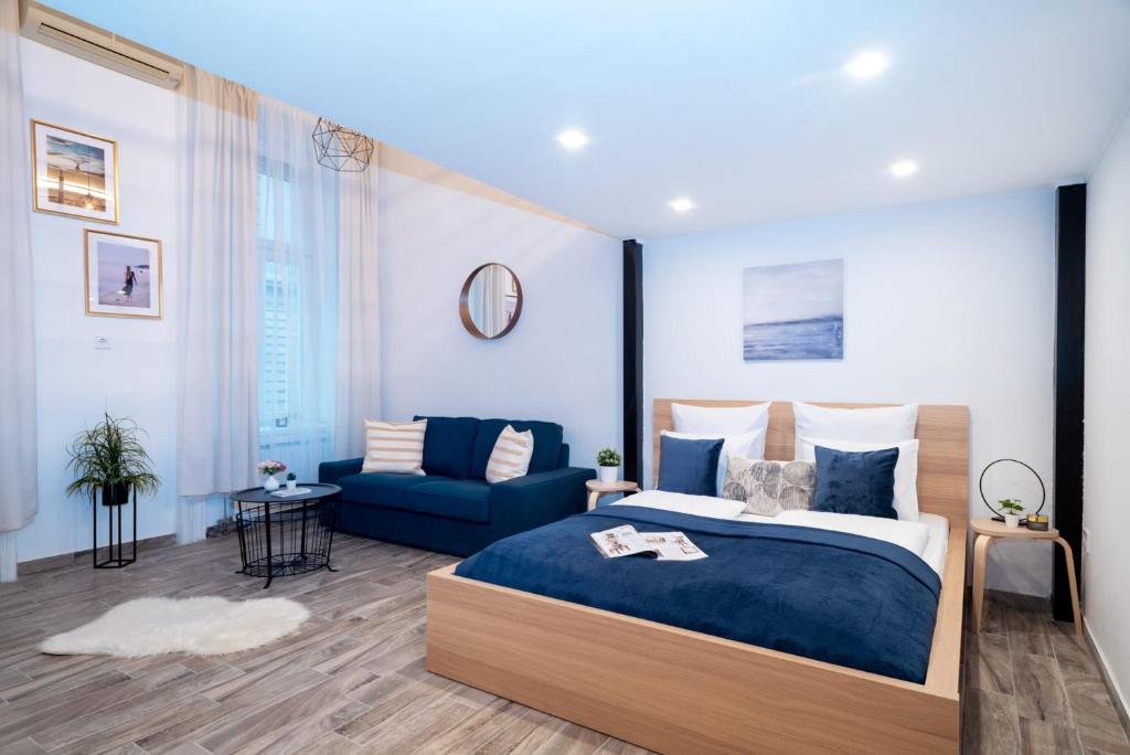 a bedroom with a large bed and a blue couch at Welcoming modern apartment in the center in Budapest