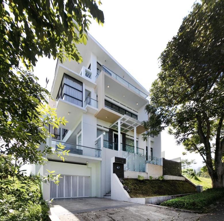 萬隆的住宿－Villa DagoResor Kanata 7BR 45peop Private Infinity Pool & Roof Garden，前面有树木的白色房子