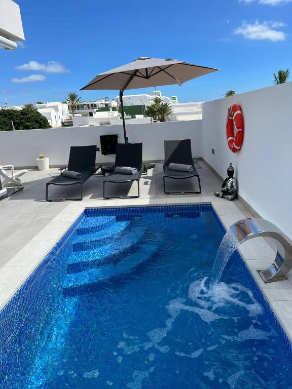 a swimming pool with an umbrella on a roof at Beach Paradise in Tías