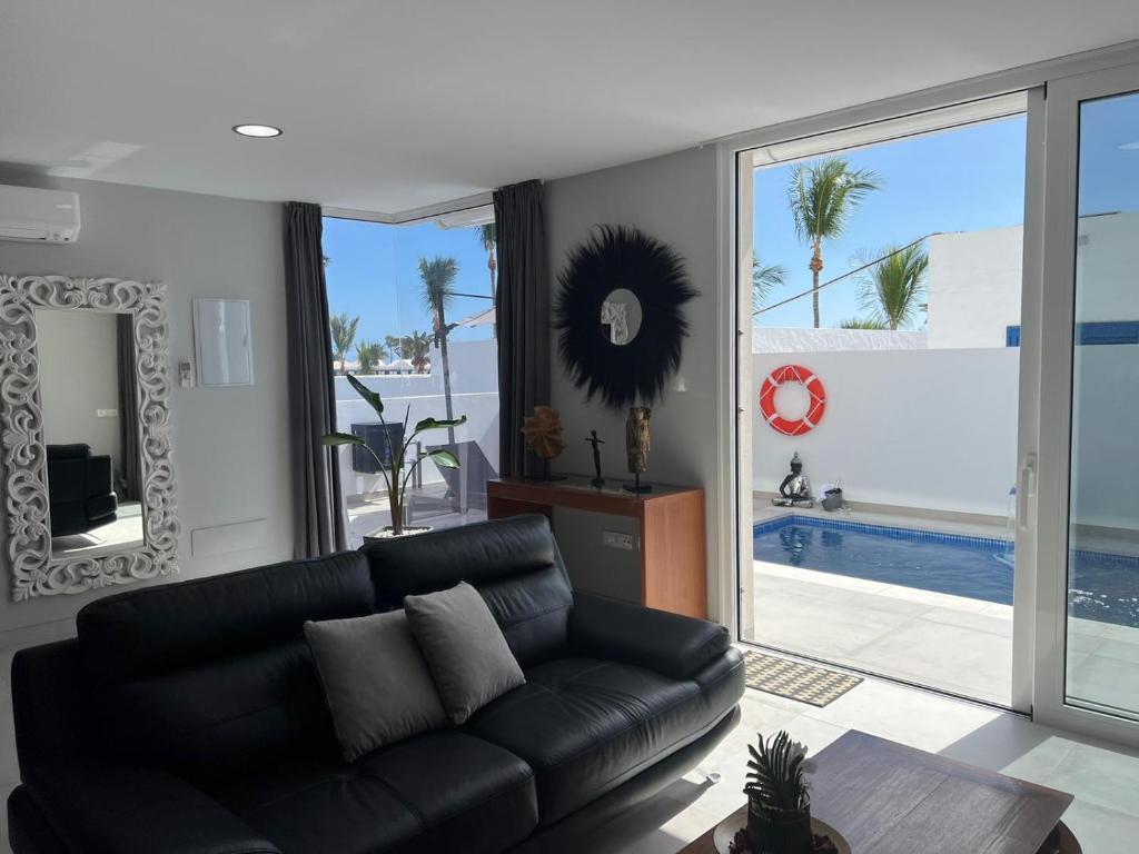 ein Wohnzimmer mit einem schwarzen Ledersofa und einem Pool in der Unterkunft Beach Paradise in Tías