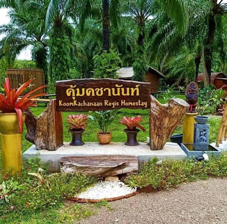 a sign in a garden with potted plants at Koom Kachanaan in Ban Nong Thale