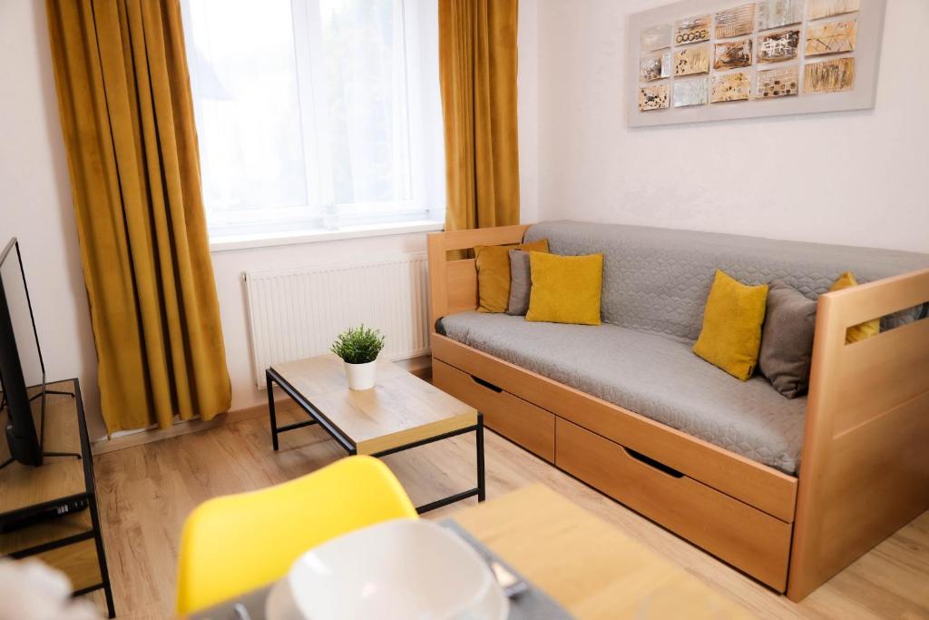 ein Wohnzimmer mit einem Sofa und gelben Kissen in der Unterkunft Apartmán 4, K Lanovce in Jáchymov
