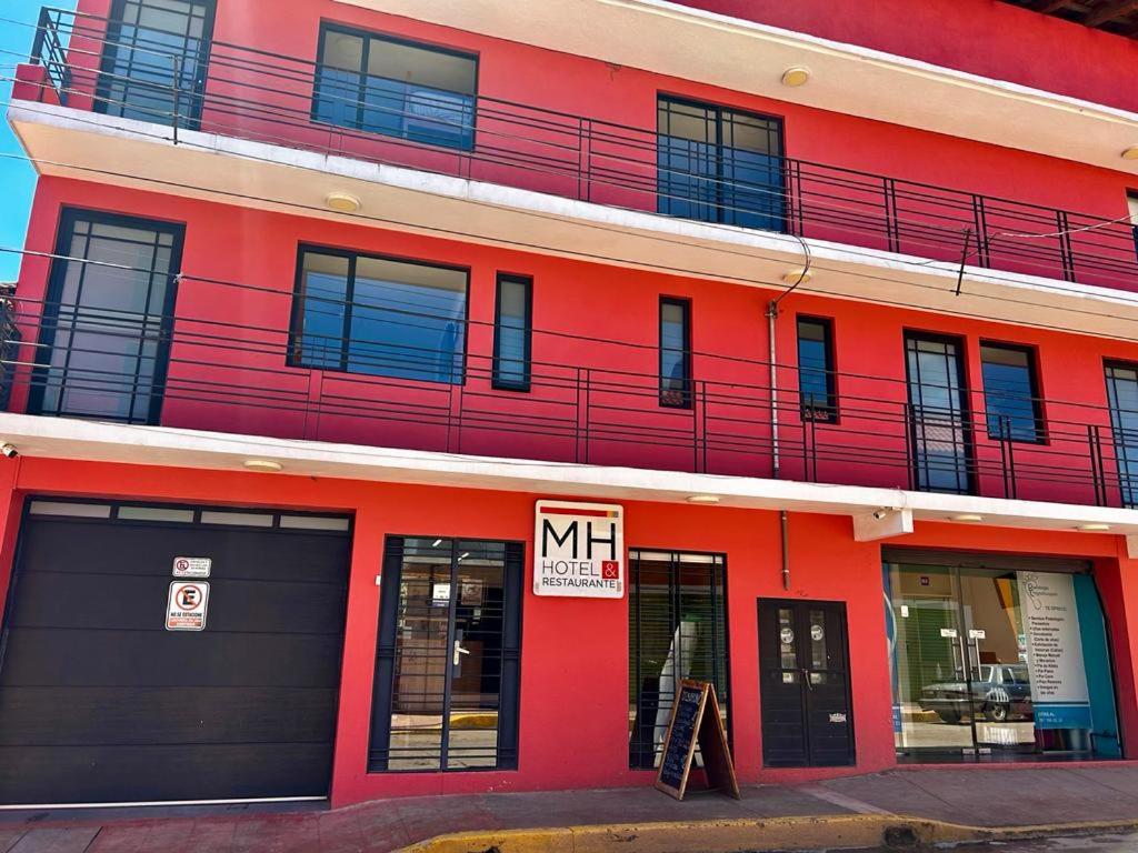 Un bâtiment rouge avec un panneau d'affichage dans l'établissement Hotel MH, à Chignahuapan