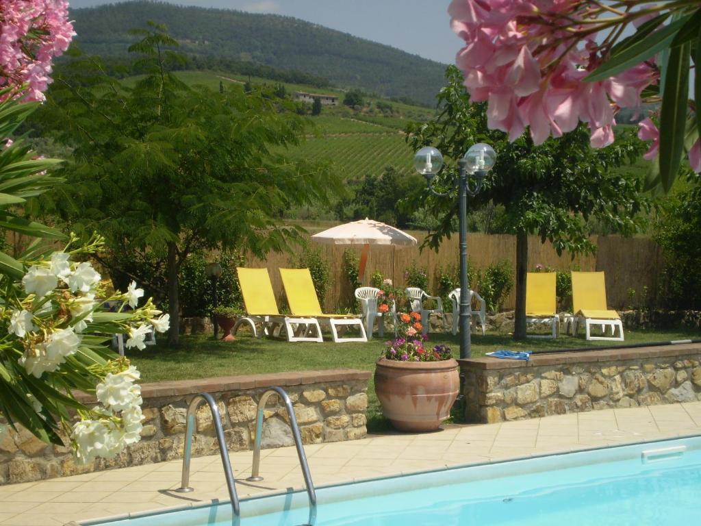 una piscina in un cortile con sedie e ombrellone di Nido Del Merlo a Santomato