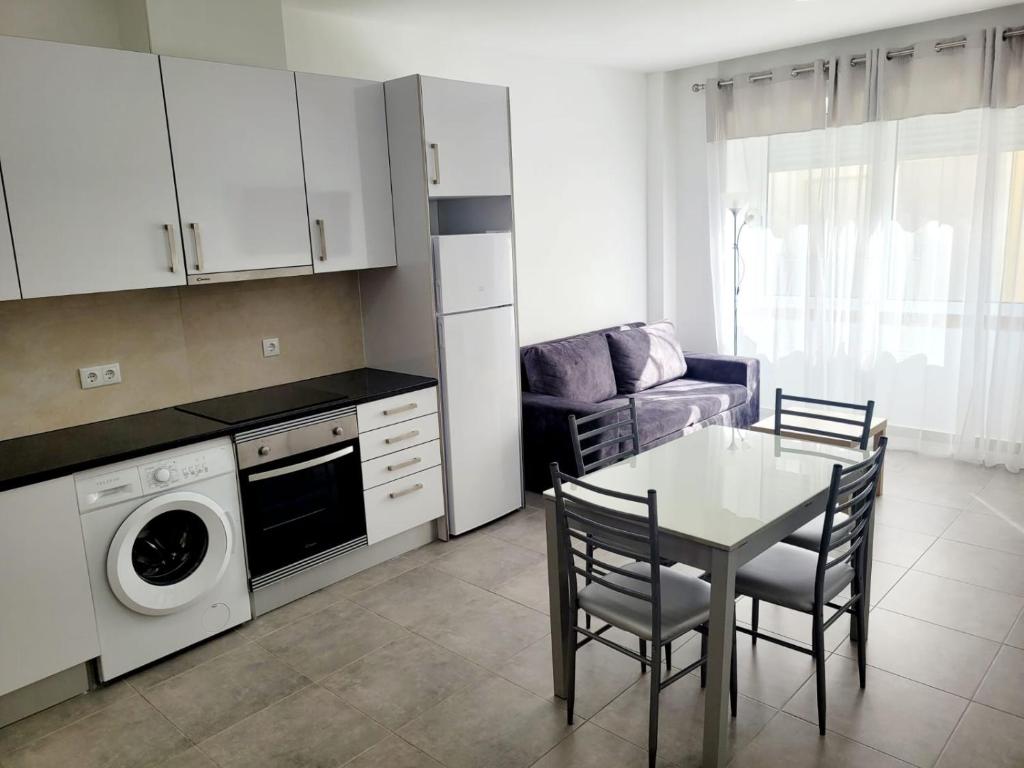 a kitchen and living room with a table and a washing machine at Penedo Grande suítes T2 in São Bartolomeu de Messines