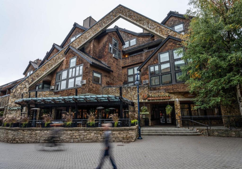 una persona passa davanti a un grande edificio con un negozio di Executive Inn Whistler a Whistler