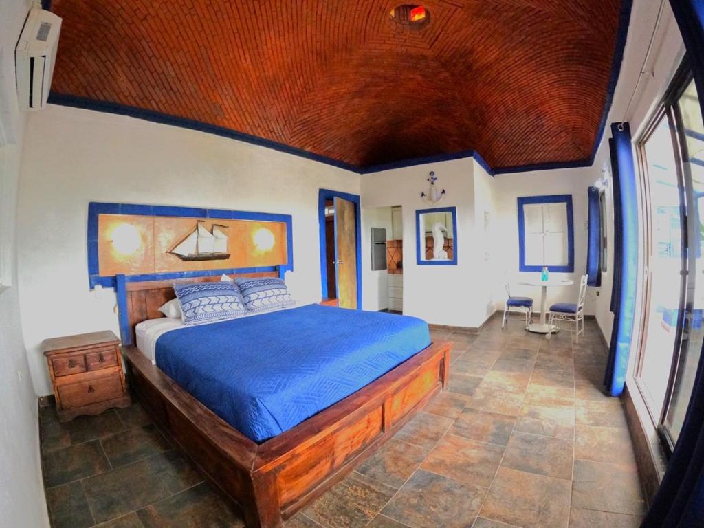 1 dormitorio con 1 cama grande y edredón azul en Selenes Hostel en El Sargento