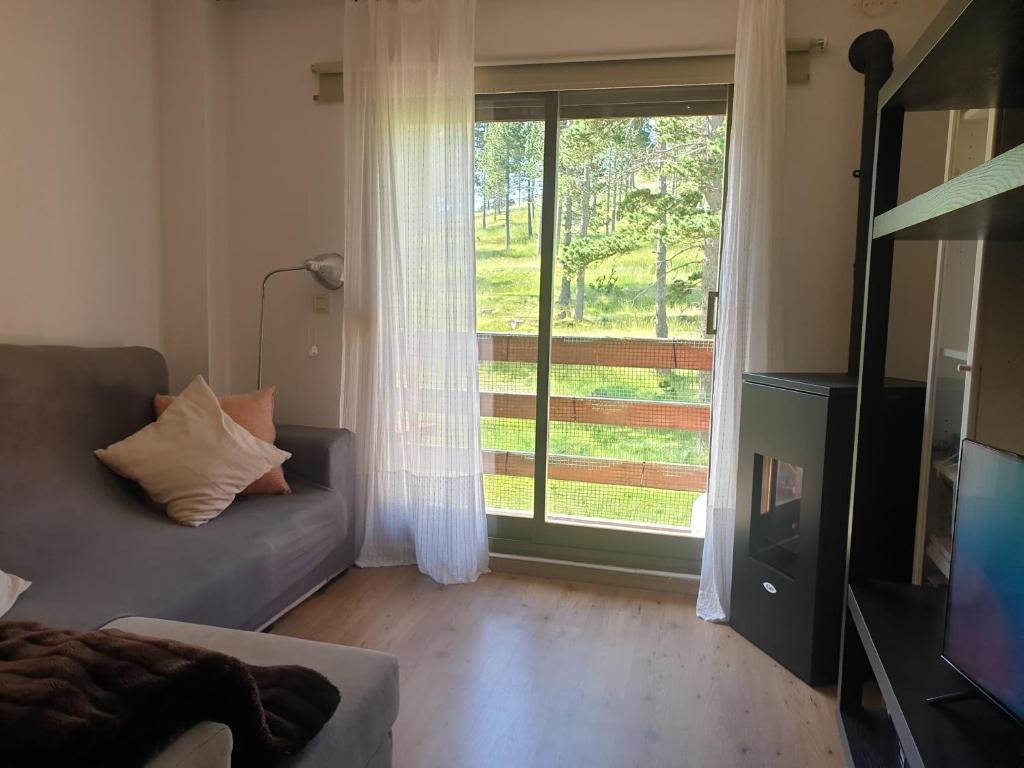 uma sala de estar com um sofá e uma grande janela em Port del Comte Apartment - A PIE DE PISTA em La Coma i la Pedra