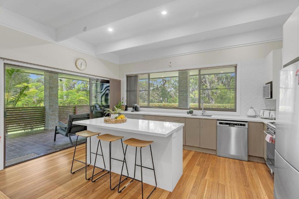 a kitchen with a white counter and stools at Husky Days in Huskisson