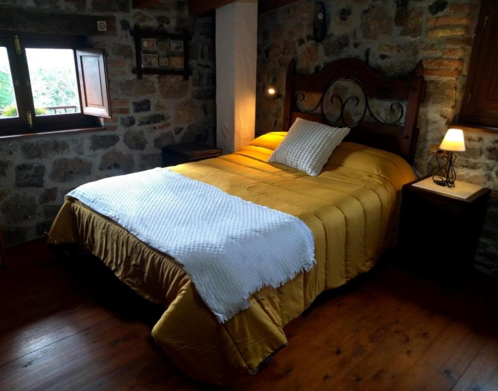 a bed in a room with a stone wall at Casa Rural El Cotu en Cangas de Onís in Cangas de Onís