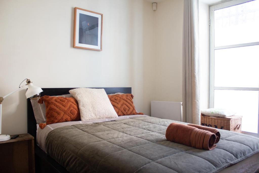 Cozy bedroom in Clapton home في لندن: غرفة نوم مع سرير كبير مع وسائد برتقالية