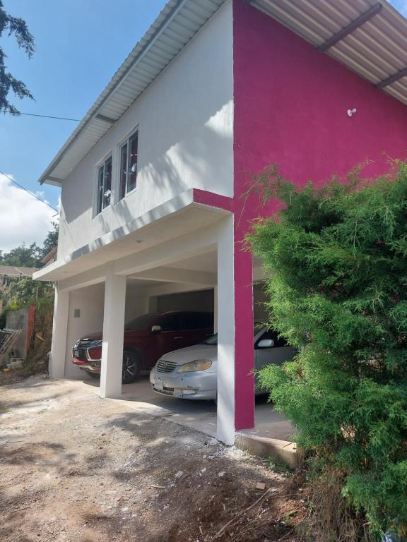 a white and pink house with a car garage at Casa non in Guatemala