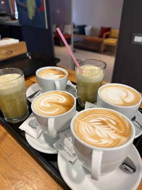 3 Tassen Kaffee auf einem Tablett mit Getränken in der Unterkunft Bejart Apartment 4 in Tirana