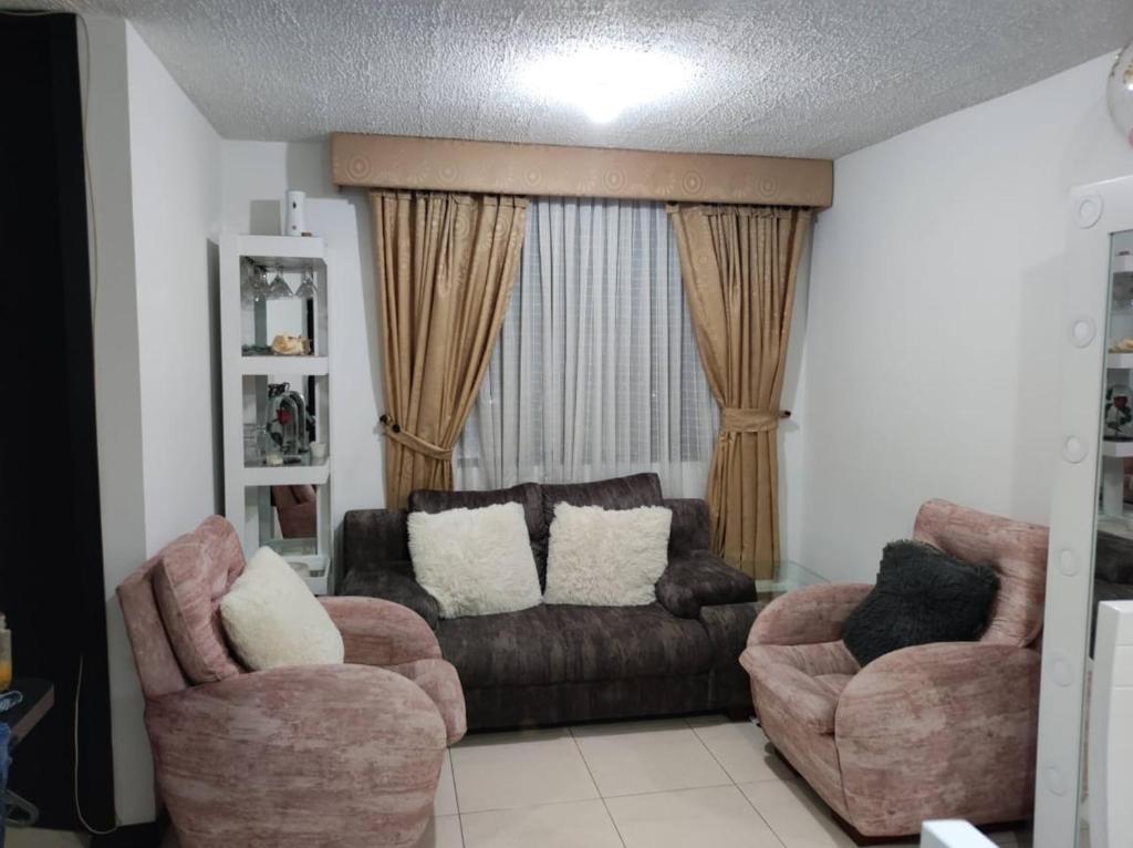 een woonkamer met een bank en 2 stoelen bij APARTAMENTO CERCA A LA SENDA DEL CARNAVAL in Pasto