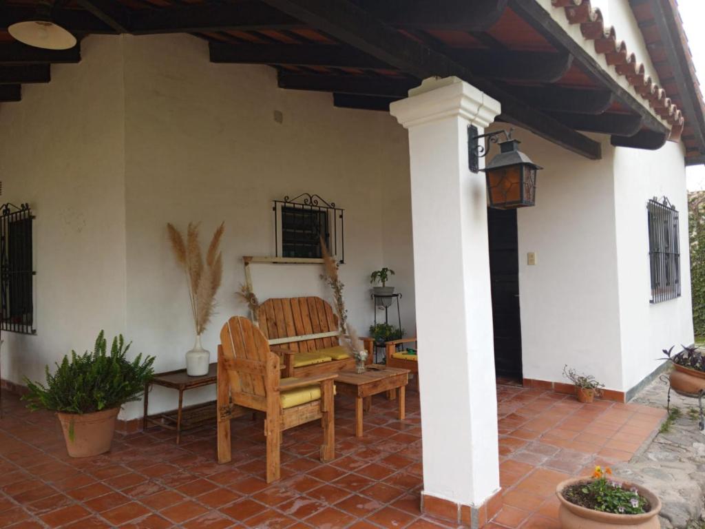 een veranda met een stoel en een bank op een patio bij La Posada de los Vallistos - Casa de Campo en El Mollar Chicoana 