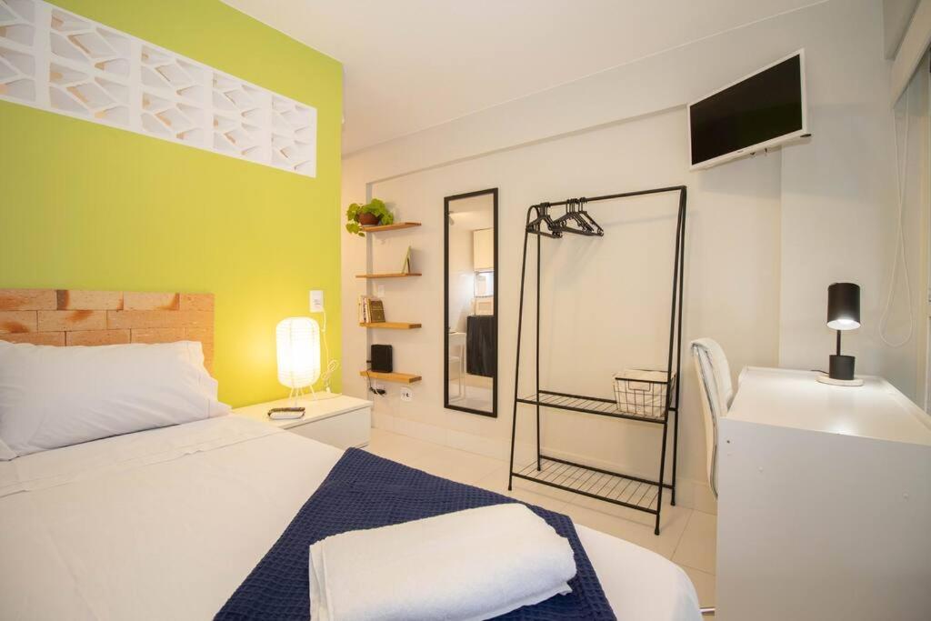 um quarto com uma cama branca e uma parede verde em Studio na melhor quadra da Asa Norte em Brasília