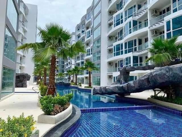 a swimming pool with palm trees in front of a building at Grand Avenue Pattaya in Pattaya Central