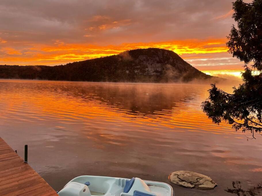 łódź siedząca na jeziorze o zachodzie słońca w obiekcie Chalet de Mimi w mieście Coaticook