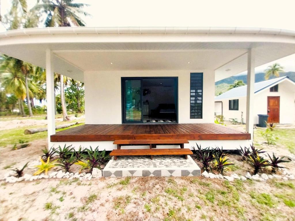 ein Haus am Strand mit einer Holzterrasse in der Unterkunft MOOREA - O Motu in Temae