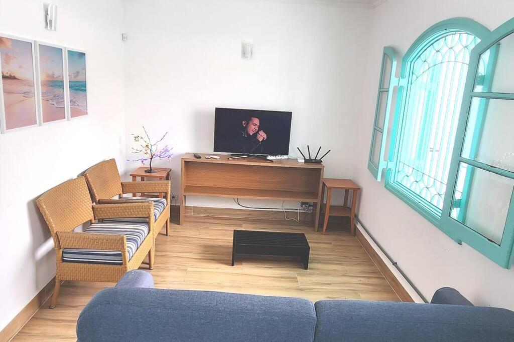 sala de estar con 2 sofás y TV en Casa pertinho da praia com piscina e churrasqueira en Peruíbe