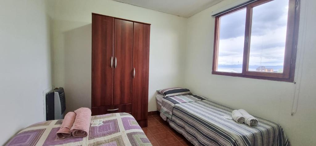 een slaapkamer met 2 bedden en een raam bij CASA COMPLETA 2 PLANTAS CON EXTRAORDINARIA VISTA AL CANAL BEAGLE CENTRICA 4pax in Ushuaia